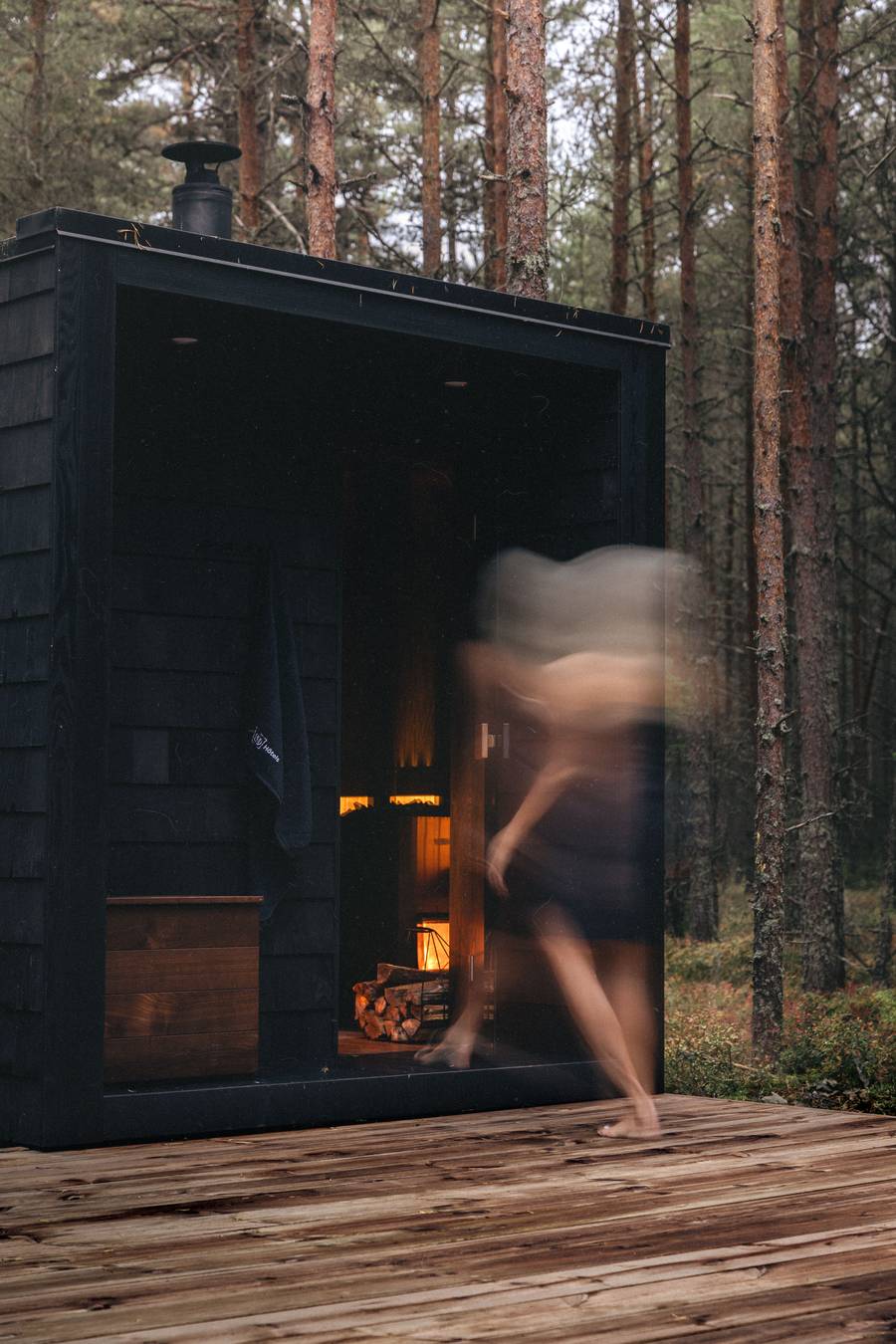Külaline astub musta sauna, ahjutuli kumab klaasi taga